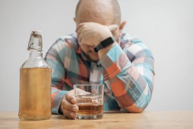 Masada bir bardak alkol, viski ya da brendi, alkolizm ve kötü alışkanlıklar ile bağımlı ve sarhoş bir adam var..