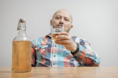 Masada bir bardak alkol, viski ya da brendi, alkolizm ve kötü alışkanlıklar ile bağımlı ve sarhoş bir adam var..