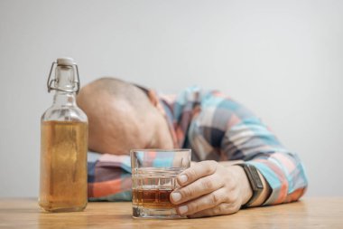 Masada bir bardak alkol, viski ya da brendi, alkolizm ve kötü alışkanlıklar ile bağımlı ve sarhoş bir adam var..