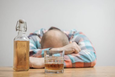 Masada bir bardak alkol, viski ya da brendi, alkolizm ve kötü alışkanlıklar ile bağımlı ve sarhoş bir adam var..