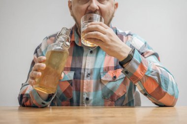 Masada bir bardak alkol, viski ya da brendi, alkolizm ve kötü alışkanlıklar ile bağımlı ve sarhoş bir adam var..