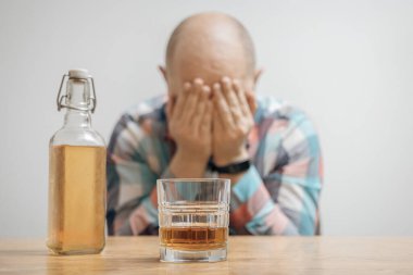 Masada bir bardak alkol, viski ya da brendi, alkolizm ve kötü alışkanlıklar ile bağımlı ve sarhoş bir adam var..