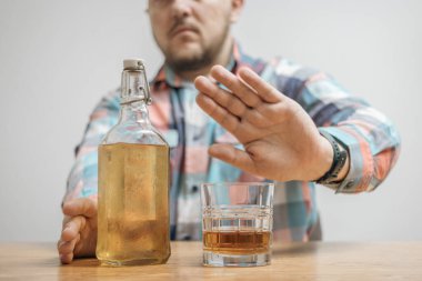 Alkolü, bardağı, alkollü içeceği ve bir şişe viskiyi veya brendiyi reddeden adam, alkolizm ve kötü alışkanlıklar.
