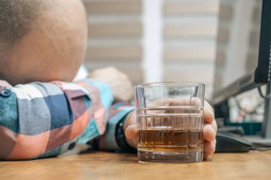 Ofiste çalışan sarhoş ve hayal kırıklığına uğramış bir adam, çalışma masasında bir bardak alkol, viski ya da brendi, alkolizm ve kötü alışkanlıklarla oturuyor..
