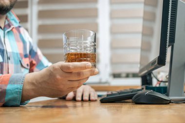 Ofiste çalışan sarhoş ve hayal kırıklığına uğramış bir adam, çalışma masasında bir bardak alkol, viski ya da brendi, alkolizm ve kötü alışkanlıklarla oturuyor..
