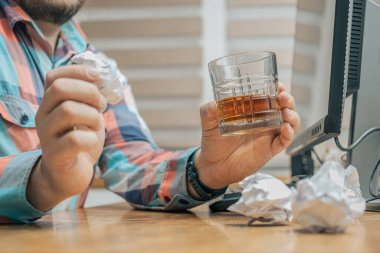 Ofiste çalışan sarhoş ve hayal kırıklığına uğramış bir adam, çalışma masasında bir bardak alkol, viski ya da brendi, alkolizm ve kötü alışkanlıklarla oturuyor..