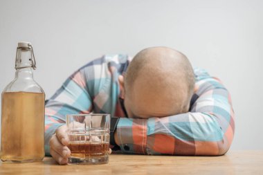 Masada bir bardak alkol, viski ya da brendi, alkolizm ve kötü alışkanlıklar ile bağımlı ve sarhoş bir adam var..