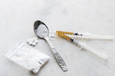 Bir kaşıkta narkotik maddeler şeffaf plastik torbada uyuşturucu tozu, dokulu arka planda dozda uyuşturucu ve beyaz haplarla dolu şırıngalar. Bağımlılık ve kötü alışkanlıklar kavramı.