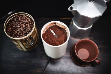 Elektrikli kahve öğütücüsünde, ahşap bir masada kahve demliği ve kahve hazır..