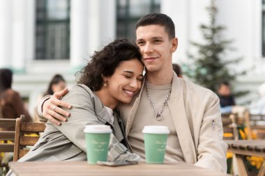 Bir kafede mutlu bir çift. Sarılmak, gülümsemek, masada kahve içmek. Sonbahar atmosferi