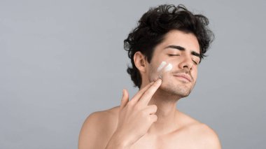 Sakallı beyaz bir adam yüz maskesi yapıyor.