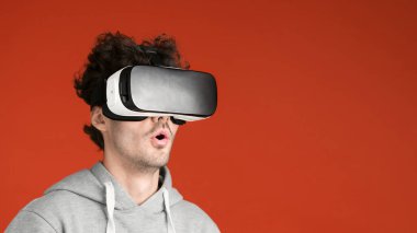 Genç bir adam VR gözlük takarken heyecanlanıyor, kırmızı arka plan