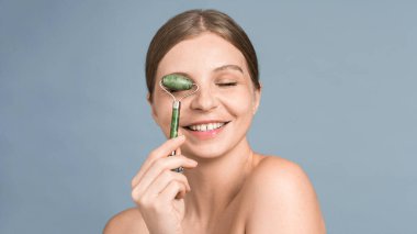 Yüz masajı için tekerlekli sandalyede poz veren beyaz bir kadın.