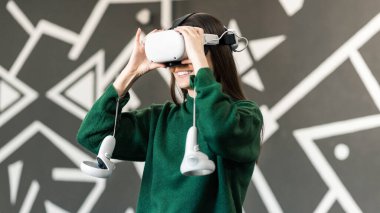 VR gözlüklü genç bir kadın VR oyunları oynarken heyecanlanıyor