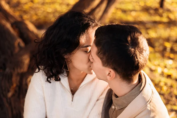 공원에서 로맨틱 커플이지 줄기에 앉아서 키스하고 가을의 분위기 누르스름 주위를 — 스톡 사진