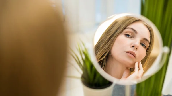 stock image A young caucasian woman is looking in the mirror and posing