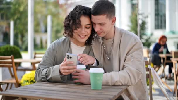 Szczęśliwa Para Pobliżu Kawiarni Patrząc Telefon Uśmiechając Się Rozmawiając Pijąc — Wideo stockowe