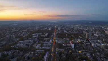Chisinau 'nun gün batımında Moldova' daki hava aracı görüntüsü. Birden fazla bina ve meydanlı şehir merkezi manzarası. Sarı ağaçlı, hareketli arabalı yollar ve aydınlatma.