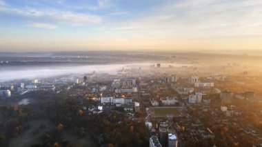 Chisinau 'nun güneş doğarken Moldova' daki hava aracı görüntüsü. Gökyüzü sisli, binalar, meydanlar ve caddeler sararmış ağaçlarla kaplı.
