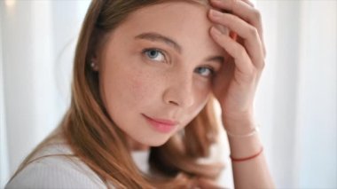 Genç beyaz bir kadın gözlerinin altına yamalar yerleştiriyor. Cilt bakımı teması