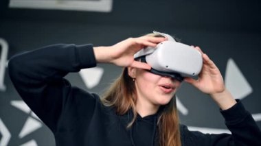 VR gözlüklü genç bir kadın VR oyunları oynarken heyecanlanıyor. Yavaş çekim
