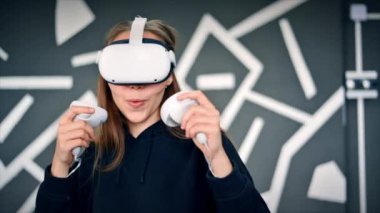 VR oyunlarıyla ilgilenen genç bir kadın VR gözlük ve kumanda kullanıyor. Yavaş çekim