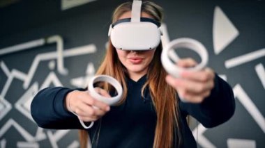 VR oyunlarıyla ilgilenen genç bir kadın VR gözlük ve kumanda kullanıyor. Yavaş çekim