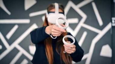 VR oyunlarıyla ilgilenen genç bir kadın VR gözlük ve kumanda kullanıyor. Yavaş çekim