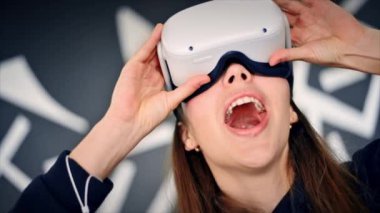 VR gözlüklü genç bir kadın VR oyunları oynarken heyecanlanıyor. Yavaş çekim