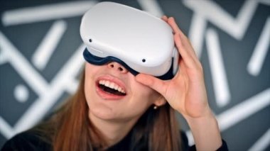 VR gözlüklü genç bir kadın VR oyunları oynarken heyecanlanıyor. Yavaş çekim