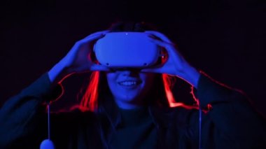 VR gözlük ve kumanda kullanarak VR oyunlarında oynayan genç bir kadın, kırmızı ve mavi ışıklandırma. Yavaş çekim
