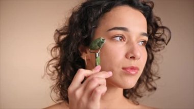 Kafkasyalı genç bir kadın silindir kullanarak yüz masajı yapıyor. Yavaş çekim