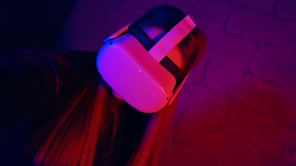 Vrメガネとコントローラーを使ってVrゲームで遊ぶ若い女性 赤と青の照明 スローモーション — ストック動画