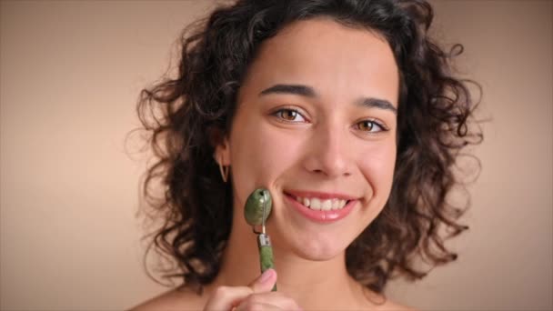 Μια Νεαρή Καυκάσια Χαμογελαστή Γυναίκα Κάνει Μασάζ Προσώπου Χρησιμοποιώντας Έναν — Αρχείο Βίντεο