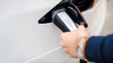 CHISINAU, MOLDOVA - NOVEMBER, 2022: Tesla Model S şarj eden bir adamın yakın görüntüsü