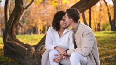 Sonbahar parkında romantik bir çift. Adam kadınını öpüyor. Sonbahar atmosferi, sarı ağaçlar ve yapraklar. Yavaş çekim