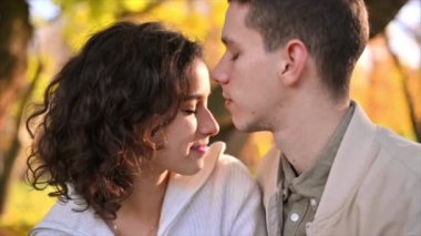 Sonbahar parkında romantik bir çift. Adam kadınını öpüyor. Sonbahar atmosferi, sarı ağaçlar ve yapraklar arka planda. Yavaş çekim