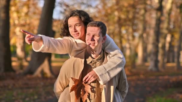 공원에서 로맨틱 커플이지 여자를 남자가 웃으면서 무언가를보여 있습니다 가을의 분위기 — 비디오
