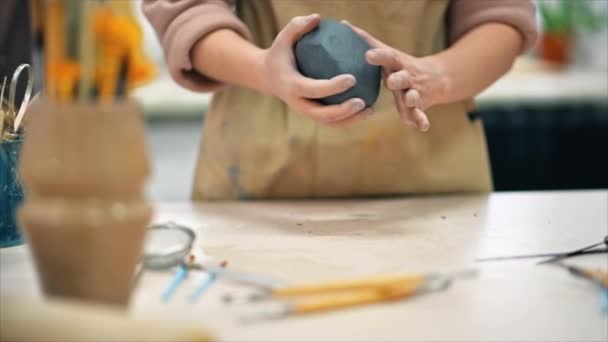 工房で働く陶器の彫刻の達人 彼女の手で粘土の一部を混練 テーブルの上のツール スローモーション — ストック動画