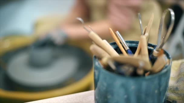 工房で陶芸作業や道具の彫刻の達人 陶芸家の車輪の上に粘土を成形します スローモーション — ストック動画