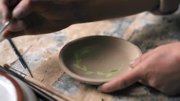 工房で働く陶器の彫刻の達人 皿の底をブラシで塗ります スローモーション — ストック動画