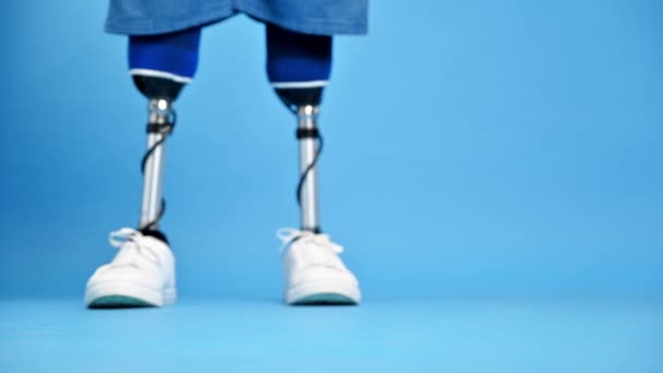 看到一个穿着假腿和白色运动鞋的男人正在做一个台阶 蓝色背景 — 图库视频影像