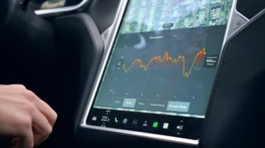 CHISINAU, MOLDOVA - Kasım 2022: bir Tesla S modelinin yavaş çekim görüntüsü. Enerji tüketimi bilgisiyle ana ekranı kullanan sürücü