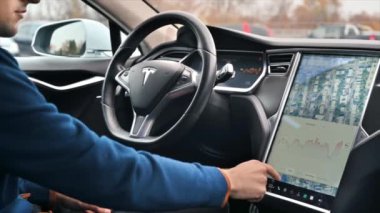 CHISINAU, MOLDOVA - Kasım 2022: bir Tesla S modelinin yavaş çekim görüntüsü. Enerji tüketimi bilgisiyle ana ekranı kullanan sürücü