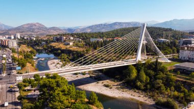 Aerial drone view of Podgorica, Montenegro. River with a bridge over it, a lot of greenery, buildings