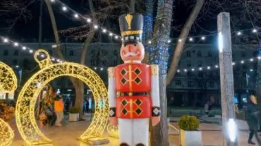 CHISINAU, MOLDOVA - DECEMBER, 2022: Timelapse view of city centre with Christmas decorations, year 2023 illuminated installation, the nutcracker statue, walking people, bare trees