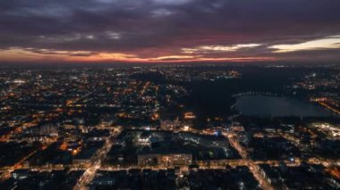 Aerial drone timelapse view of Chisinau at sunset, Moldova. View of city centre with multiple buildings, roads, lake, illumination