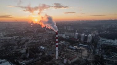 Aerial drone timelapse view of thermal power plant in Chisinau at sunrise, Moldova. View of pipe with felling steam, cityscape