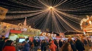 ROMANIA, SIBIU - DECEMBER, 2022: View of the Historic Centre of the town with Christmas fair. The Great Square decorated with ferris wheel, illumination, old buildings and multiple people