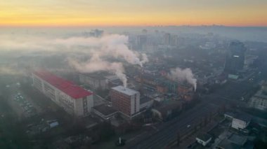 Aerial drone view of an production facility in Chisinau at sunrise, Moldova. Cityscape with multiple buildings, pipes with felling steam
